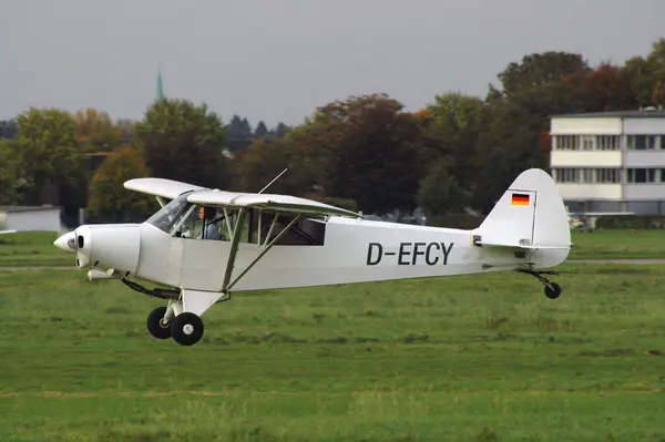 stock image Motorized aircraft flies just over the grass runway