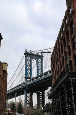 Brooklyns DUMBO 'dan Manhattan Köprüsü manzaralı bir kar yağışı. Karla kaplı sokaklar, rıhtım ve ikonik köprü yapısı Manhattan ufuk çizgisine karşı sakin bir kış manzarası yaratıyor..