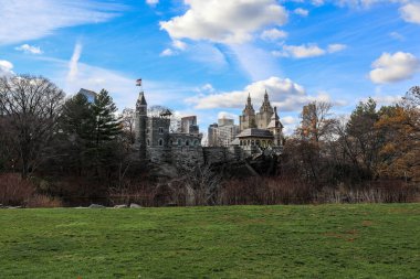 Central Park, Manhattan, New York 'taki Belvedere Kalesi' nin manzarası. Tarihi taş yapı, parkların yeşillik ve göletlere bakıyor. Mimari cazibeyi, hareketli şehir manzarasının merkezindeki doğal güzellikle harmanlıyor..