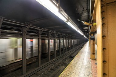 New York Citys metro sisteminin dinamik bir görüntüsü, trenlerin hareket halindeki bir istasyona ulaşması ve yolcuların platformları kullanması. Sahne, NYC kentsel yaşamında toplu taşımanın enerjisini, hareketini ve temel rolünü yakalıyor..