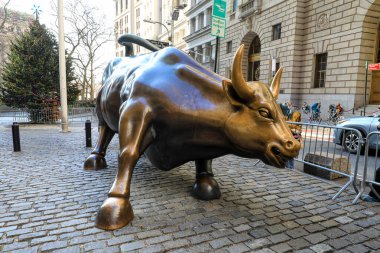 Manhattan Finansal Bölgesi, New York 'taki Charging Bull heykelinin ikonik görüntüsü. Bronz heykel, hareketli sokaklar, yayalar ve Aşağı Manhattan 'ın dinamik kentsel çevresiyle çevrili güç ve finansal iyimserliği simgeliyor..