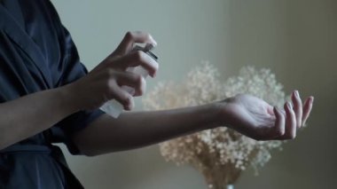 Parfüm sıkan bir kadın. Genç bir bayan kolonya sürüyor, bileklerine parfüm sürüyor, vücuduna kadınsı güzel kokular sürüyor. Cilt bakımı ve vücut bakımı kavramı.
