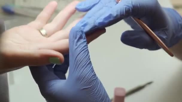 手袋のマニキュアアーティスト 爪を磨く ネイルポーランドのハンド マネジストはゲルポーランド語で爪を塗ります — ストック動画