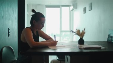 Masada oturan kağıt üzerine resim yapan bir kadın. Dövme sanatçısı dövme için eskiz yapıyor. Dişi dövme ustası stüdyoda gelecek dövme fikri üzerinde çalışıyor..
