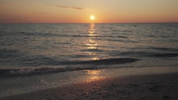 日の出に美しい海岸 水面を反射する劇的な燃える空 落ち着いた波を持つ夏のビーチパノラマ イディラックな自然の風景 高品質の4K映像 — ストック動画