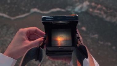 Eski film kamera görüntüleyicisinden bak. Dişi eller, geriye dönük analog tr orta formatta 120 mm 'lik kamera tutuyor ve gün doğumunda sahilde denizin fotoğrafını çekiyor. Yüksek kalite 4k görüntü.