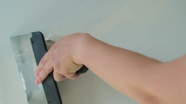 Duvara spatula yapıştıran kadın. Eklemlerin macununu tamamlamak için sıva yapan sıva ustası. DIY ev yenileme, iç tasarım konsepti. Ağır çekim. Yüksek kalite 4k görüntü
