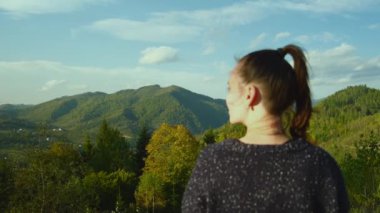 Dağ manzarasının tadını çıkaran mutlu genç bir kadın. Dişi turist tepenin zirvesine çıktıktan sonra doğanın muhteşem manzarasını hayal eder. Yüksek kalite 4k görüntü