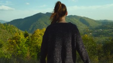 Dağın tepesinde el kaldıran bir kadın. Kadın turist kollarını havaya açıp uçurumda özgürlüğün ve hayatın tadını çıkarıyor. Kaya yürüyüşü kavramı. Yüksek kalite 4k görüntü