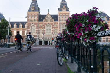 Güneşli bir öğleden sonra arka planda bisiklet yolu ve rijksmuseum 'a giden iki bisikletli Astel Nehri' nin metalik çitlerinin yanında klasik bisiklet.