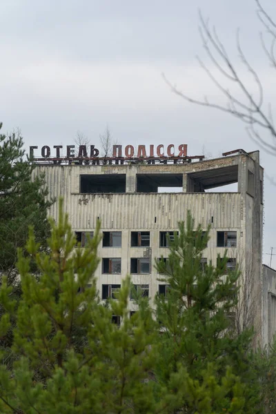 緑の高い木と放棄された建物の上にPolissyaホテルのレタリングサイン — ストック写真
