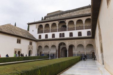 Saray avlusunda bahçeler ve turistlerle birlikte İslami mimari bir cephe.
