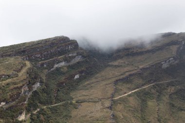 Beautiful mountain landscape with a sand road across the mountains and fog 