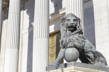 Güneşli bir günde Madrid Kongre Binası 'nda bir topun üzerinde pençesi olan güzel bir aslan heykeline yakın.