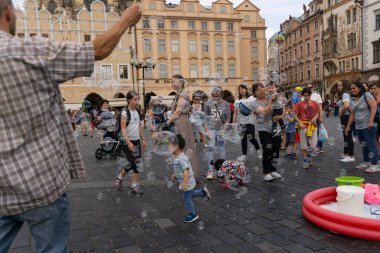 Tyn Meydanı 'nda baloncuklarla oynayan bir grup çocuk turist.