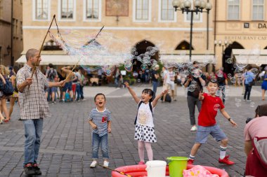 Prag Tyn Meydanı 'nda sabun köpüğüyle oynayan Asyalı çocuklar.