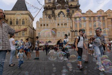Tyn Kilisesi 'nin arka planında Tyn Square' de sabun köpüğüyle oynayan bir grup çocuk.