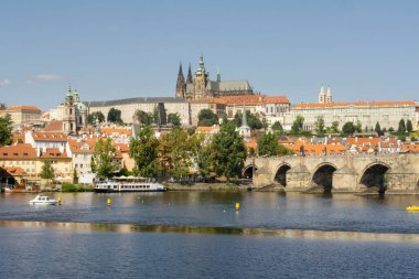 Güneşli günbatımında arka planda Prag Kalesi olan Vltava Nehri manzarası