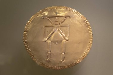 Kolombiya Müzesi 'nde göğüs kaslarının ortasında bir adamla antik yuvarlak altın pektoral.