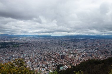 Bogota 'nın kuzeyindeki şehir manzarası güneşli bir günde La Vieja deresinden ağaçlı tepenin zirvesine çıkıyor.