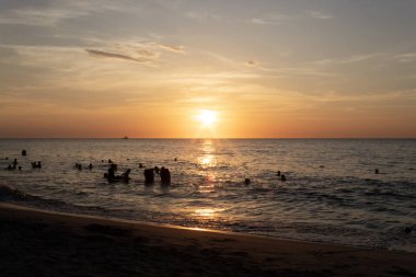 Turist silueti Santa Marta Kolombiya 'da turuncu gün batımında plaj gününün tadını çıkarıyor.