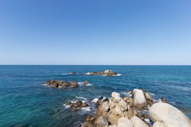 Turkuaz Karayipler 'in ortasında güneşli ve bulutsuz üç küçük kayalık tepe. 