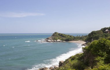 Güneşli bir günde Tayrona Ulusal Parkı 'nda kayalık dağ ve Karayip mavi deniziyle Canaveral plaj manzarası