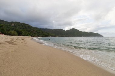 Tayrona Ulusal Parkı 'nın arka planında orman dağları olan güzel günbatımı manzarası