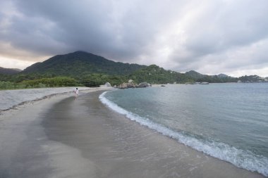 Kolombiya 'daki Tayrona Ulusal Parkı' na kurulmuş Arrecife sahilinin büyüleyici manzarası. Arka planda Karayip denizi ve orman dağları var.