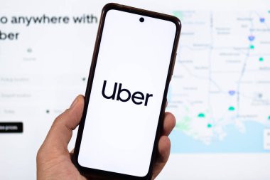 BOGOTA, COLOMBIA - 05 Mart 2025 Uber uygulama logosu ve bulanık Uber arayüz arkaplanı olan akıllı telefonu tutan bir erkek.