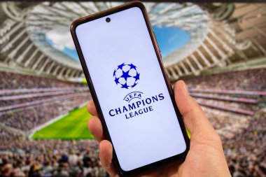 BOGOTA, COLOMBIA - 05 Mart 2025 Uefa Şampiyonlar Ligi logosu ve arka planda bulanık stadyum olan akıllı telefonu tutan bir erkek.