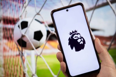 BOGOTA, COLOMBIA - Premier League futbol aslanı sembollü ve arka planda bulanık futbol topunun bulunduğu akıllı telefona yakın bir yürüyüş 05 Mart 2025