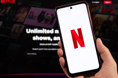 BOGOTA, COLOMBIA - 05 Mart 2025 Netflix sembolü ve netflix arkaplanda bulanık arayüzü olan akıllı telefonu tutan ele yakın çekim