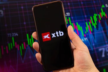 BOGOTA, COLOMBIA - 05 Mart 2025 makro fotoğraf xtb logo ile bir akıllı telefon içinde arka planda bulanık borsa