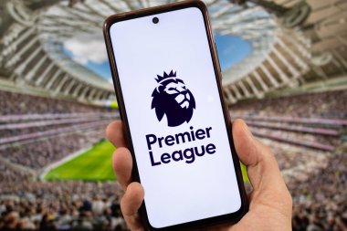 BOGOTA, COLOMBIA - 05 Mart 2025 Premier Lig futbol aslanı logosuna sahip bir akıllı telefon arka planda bulanık bir stadyum