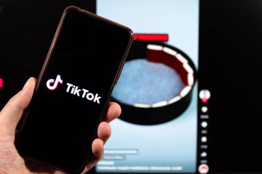 BOGOTA, COLOMBIA - 05 Mart 2025 Makro Erkek sol el ve Tik tok sosyal medya sembolü bir akıllı telefon içinde arka planda Tik tok arayüzü