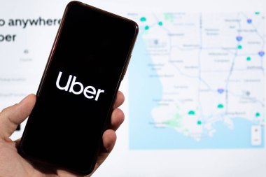 BOGOTA, COLOMBIA - 05 Mart 2025 Uber uygulama logosu ve arka planda bulanık sosyal medya arayüzü olan bir akıllı telefon