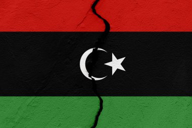 Libya devletinin bayrağı çatlamış bir duvara saplanmış. Jeopolitik ve doğal afet kavramı