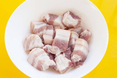 Sarı arka planda beyaz kasede domuz eti..