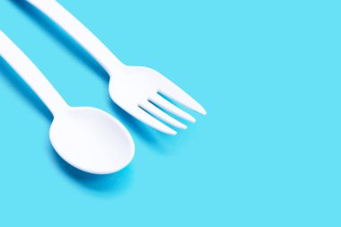 Mavi arka planda plastik çatal ve kaşık.