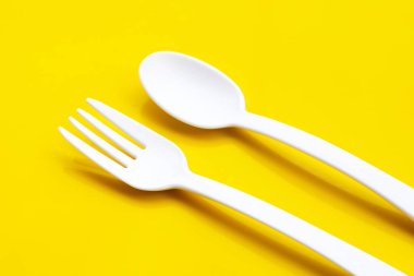 Sarı arka planda plastik çatal ve kaşık.