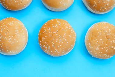 Mavi arka planda susamlı hamburger çörekleri..
