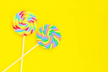 Sarı arka planda gökkuşağı lolipopu.