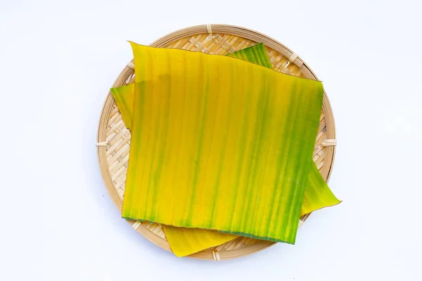 Banana leaves on bamboo weave plate on white background.