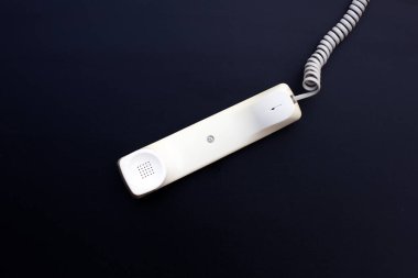 Handset of landline phone on dark background.