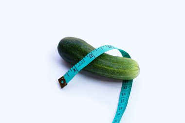 Beyaz arkaplanda mezurası olan salatalık.