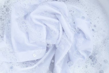 Top view of formal shirts soak in powder detergent water dissolution. Laundry concept