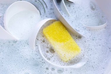Dishes and bowls in water and bubbles of dishwashing liquid