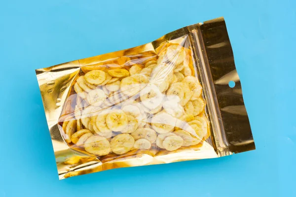 Banana slice chips  in package bag on blue background.