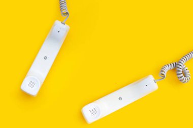 Handset of landline phones on yellow background.